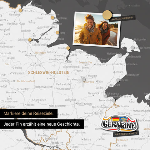 Detail einer magnetischen Deutschland-Karte als Magnettafel in Dunkelgrau zeigt Schleswig-Holstein mit einem angepinnten Urlaubsfoto sowie Reise- und Urlaubsmagnete